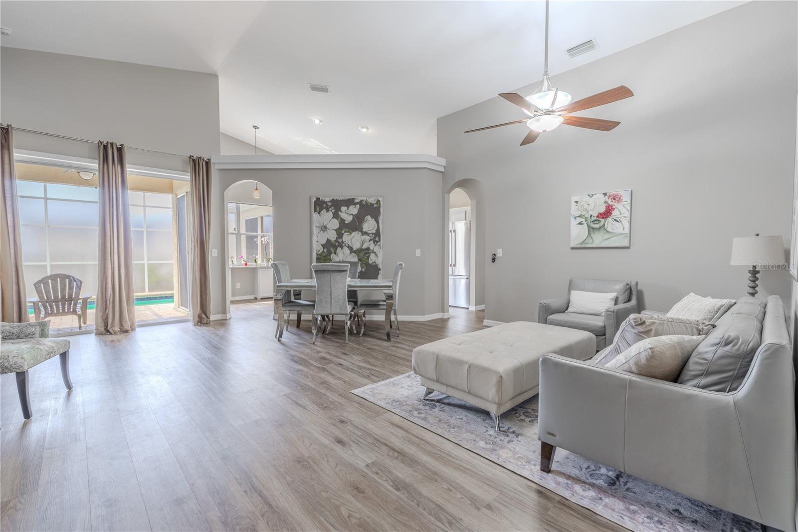 The living room and dining room are bathed in neutral tones. Sliding glass doors leading to the pool and lanai allow for plenty of natural light.