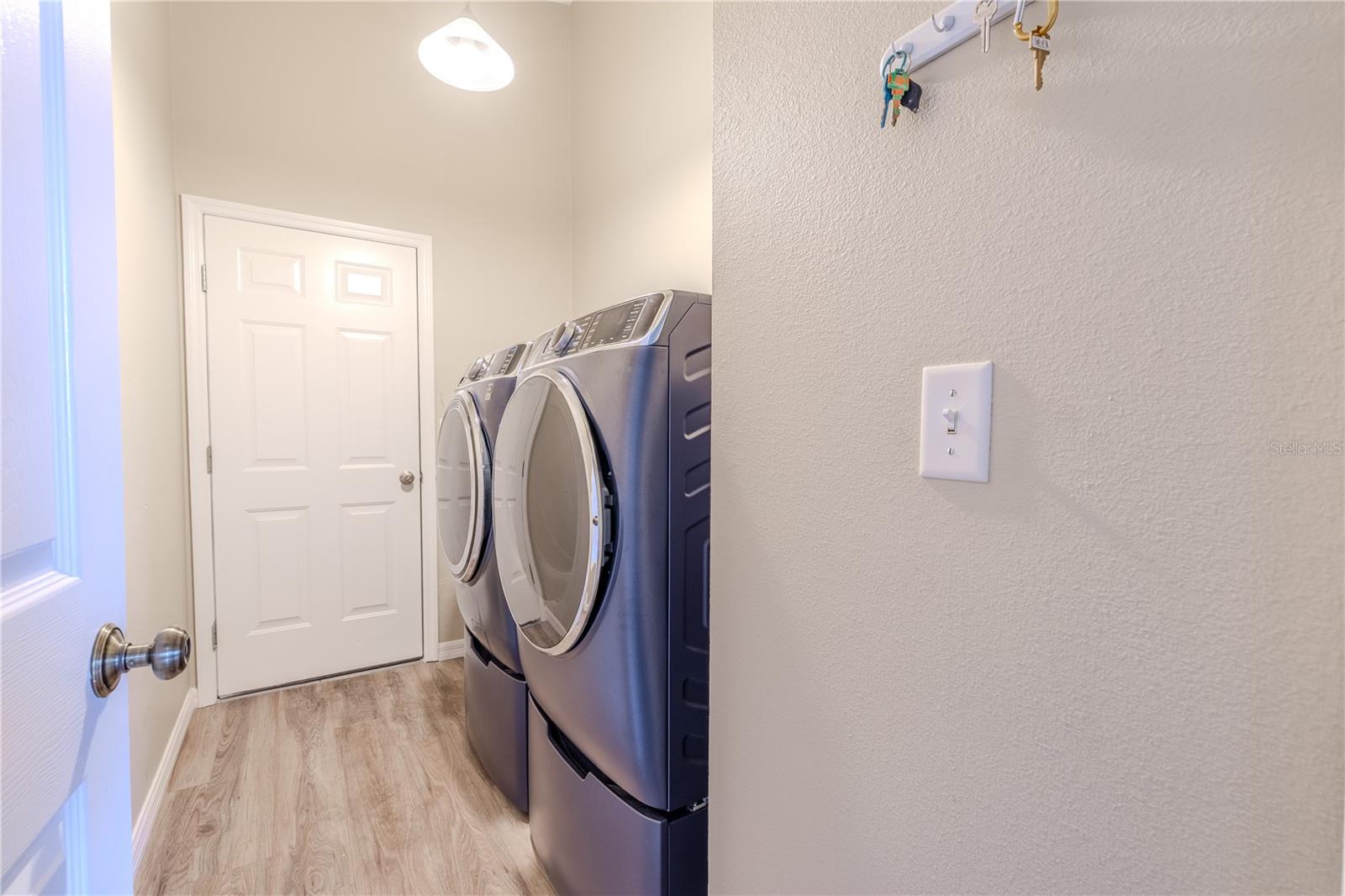 The laundry room offers convenience with a front-load washer and dryer, vinyl flooring, and access to the spacious 3-car garage.