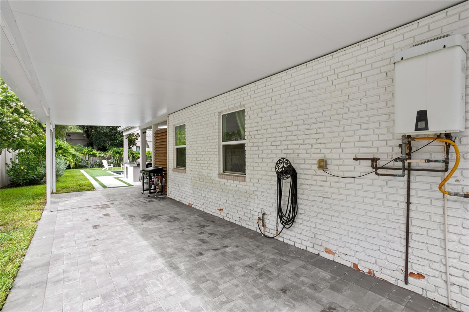 Newly added covered and paved carport situated behind vinyl fence gate for extra parking.