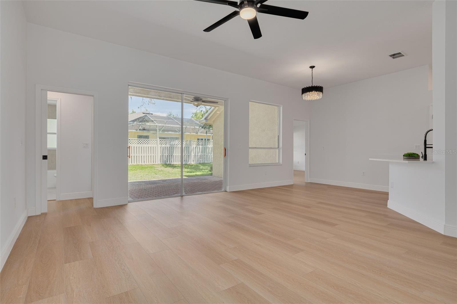 This spacious family room opens directly to the covered lanai through sliding glass doors, bringing the Florida lifestyle indoors. The new ceiling fan and elegant lighting create a comfortable retreat for relaxation and everyday living.