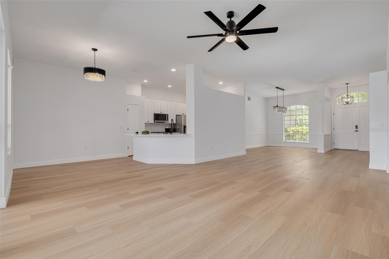 Discover the seamless flow between kitchen and living areas, perfect for modern family life and entertaining guests. Multiple chandeliers and ceiling fans with lighting provide both style and comfort throughout the expansive open floor plan.
