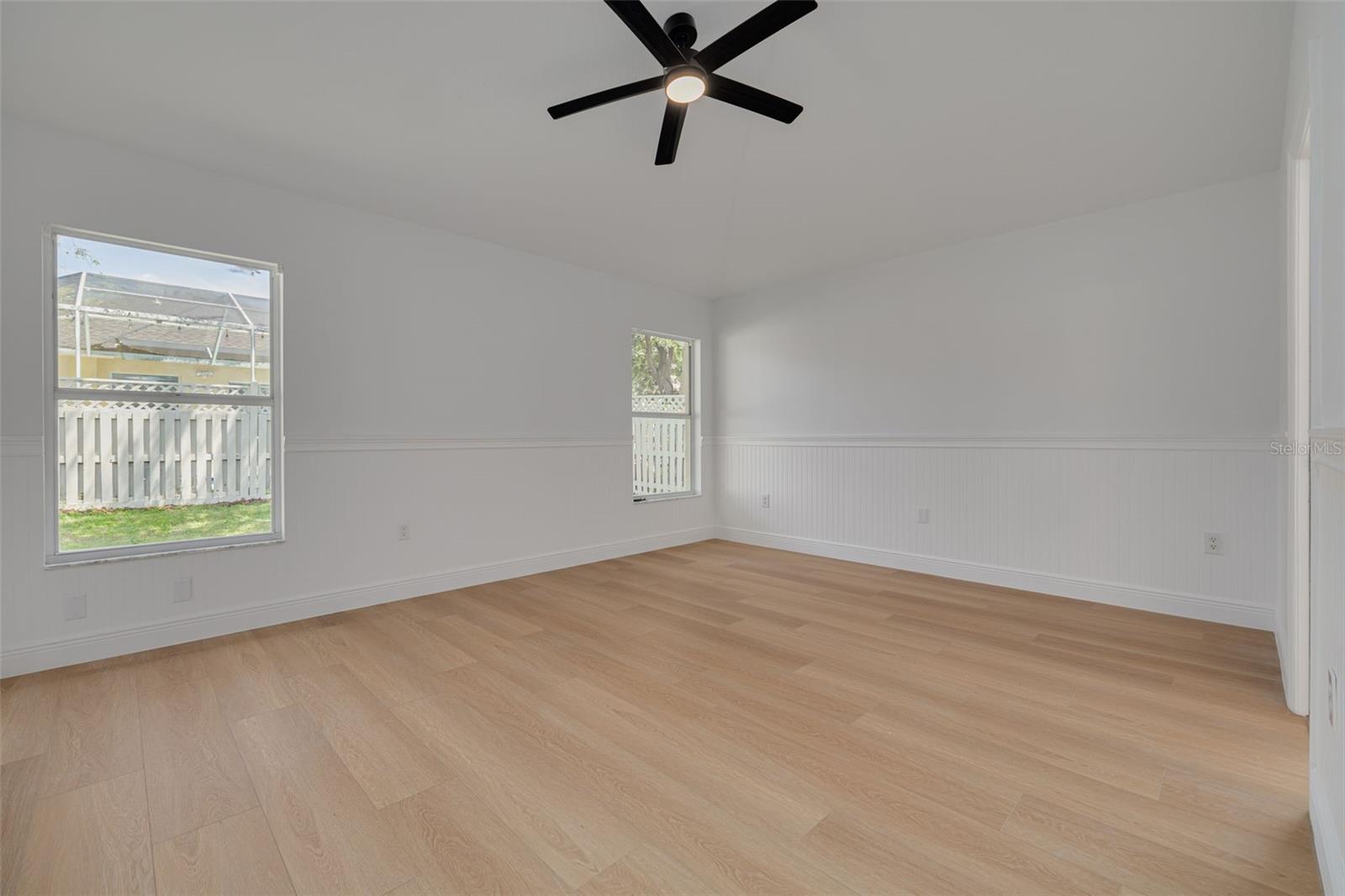 This generously sized primary bedroom features custom molding details that showcase the premium renovation throughout the home. The new ceiling fan with lighting and luxury vinyl plank flooring create a comfortable retreat for family or guests.