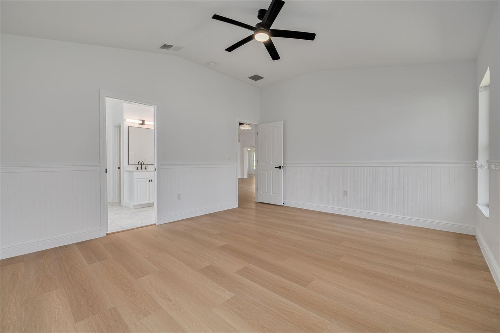 This spacious master bedroom features custom molding details and a new ceiling fan with lighting for year-round comfort. The direct access to the luxurious en-suite bathroom and quality flooring throughout create the perfect private retreat.