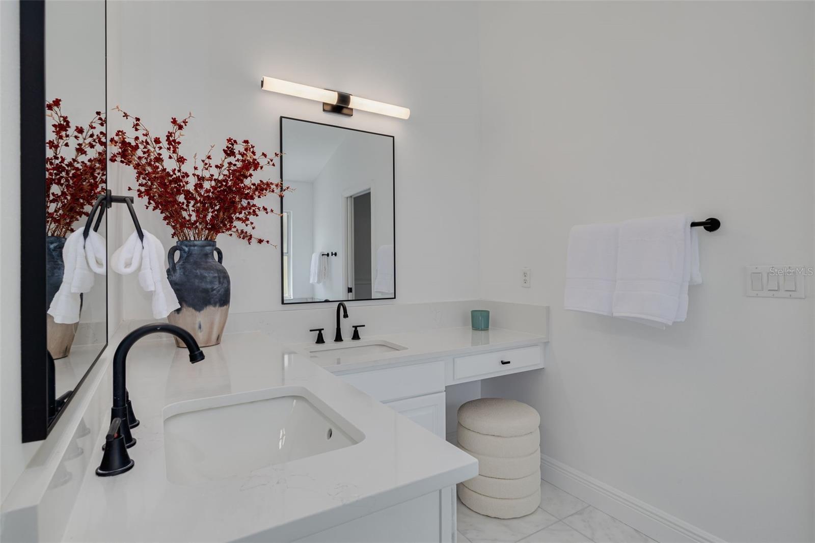 Experience luxury living with this elegant vanity featuring pristine quartz countertops and modern black fixtures that create a stunning contrast. The professional lighting and thoughtful design details make this master bathroom a true sanctuary for relaxation.