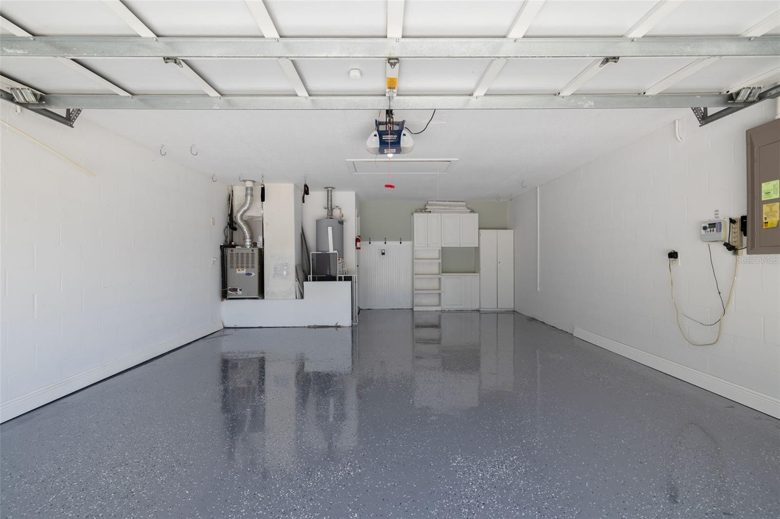 This pristine two-car garage showcases the stunning epoxy flooring that's both durable and beautiful, along with organized storage solutions. The new water heater and clean finish demonstrate the attention to detail found throughout this completely renovated home.