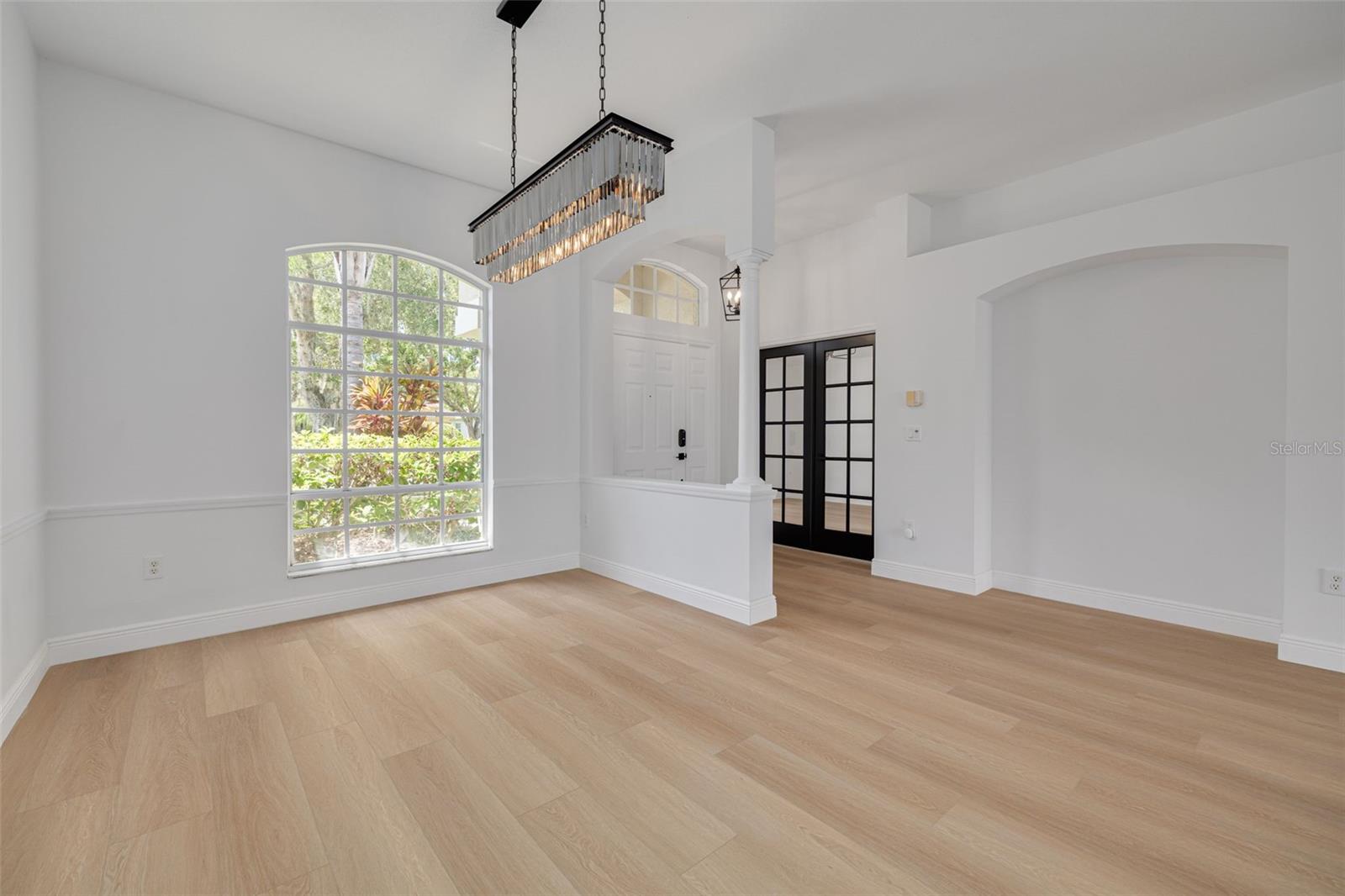 This sophisticated dining space showcases the home's elegant architectural features including arched windows that flood the room with natural light. The stunning chandelier creates the perfect ambiance for memorable dinner parties and family gatherings.