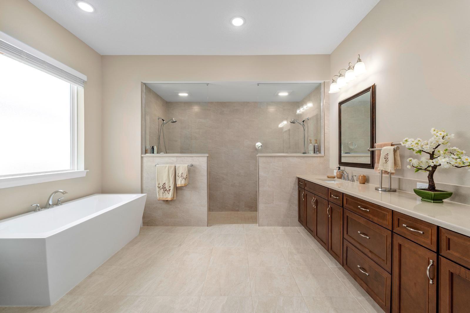The Primary Bathroom is a masterpiece of luxury! Straight ahead, there's a wall-to-wall shower with dual shower heads, to the right is the very generous vanity with dual sinks, and to the left is the stand-alone soaking tub!