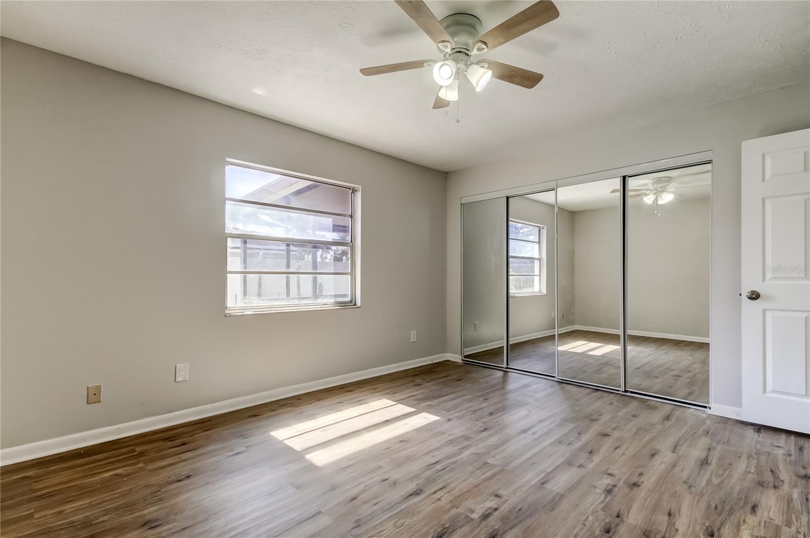 Primary bedroom with brand new flooring, ceiling fan, new mirrored closet doors with en suite bathroom.