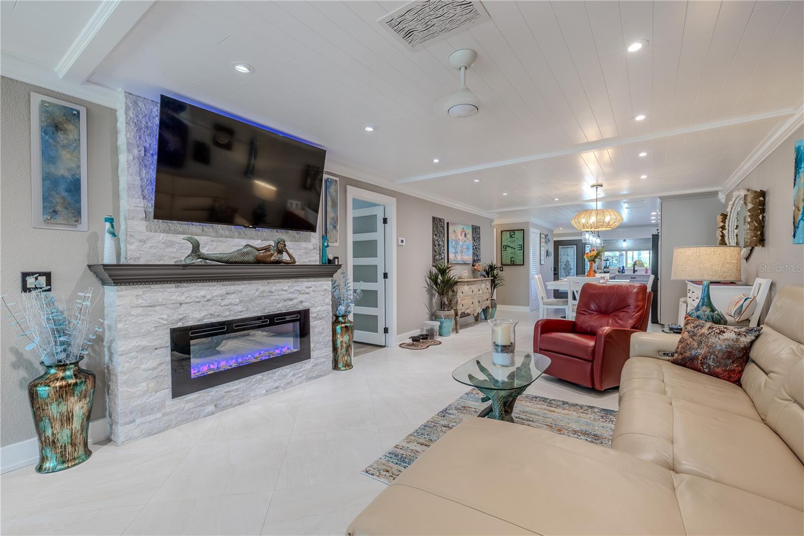 This open-concept living space showcases high-quality craftsmanship, including 5-panel solid core doors and 6” base molding carried throughout the home for a cohesive, upscale finish. A custom-built white stacked stone fireplace with a contemporary electric insert serves as a striking focal point, combining modern function with timeless design.