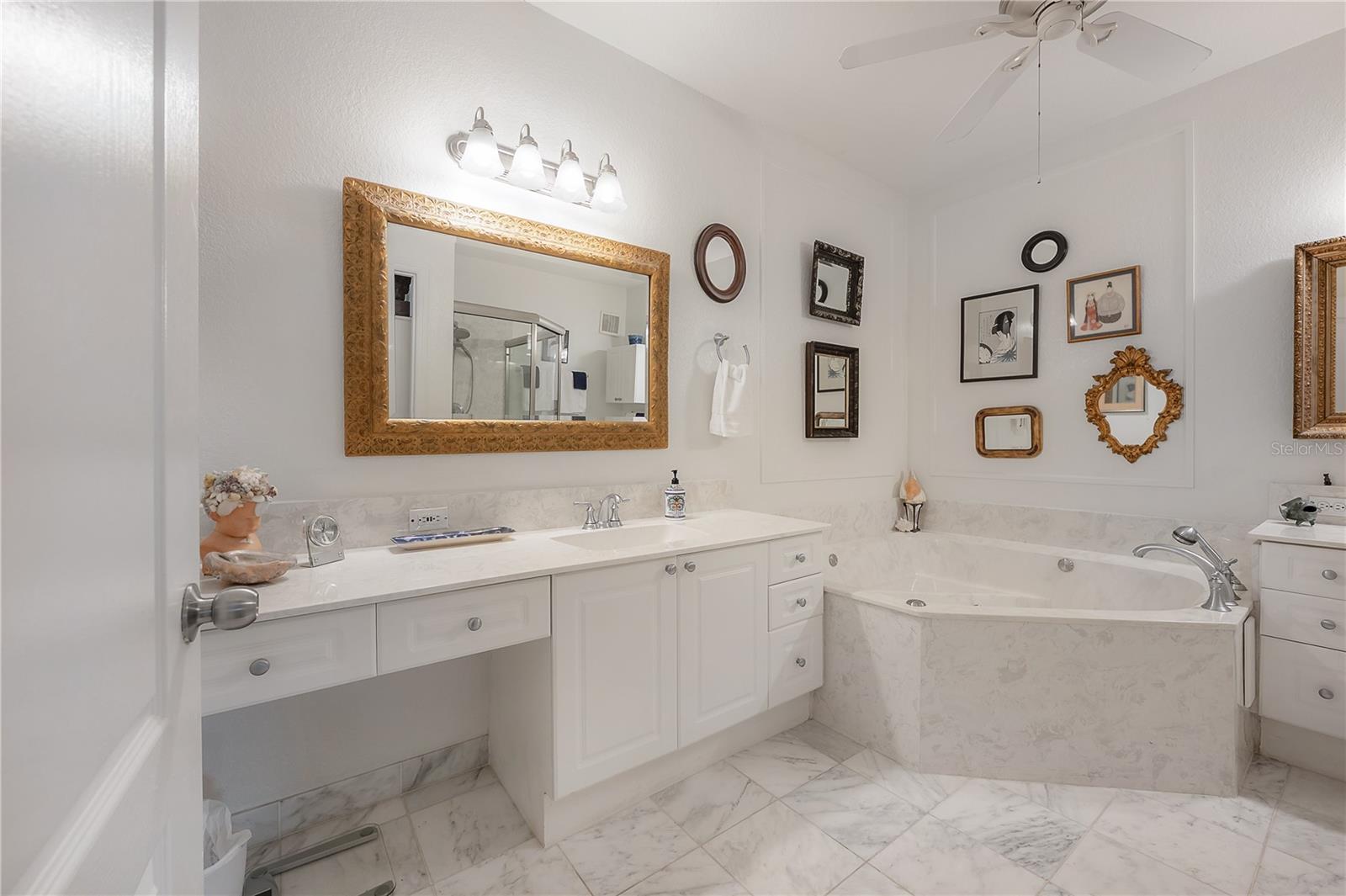 Bathroom with heated floors, dual vanities, marble flooring, jetted whirlpool tub, and and walk-in shower.