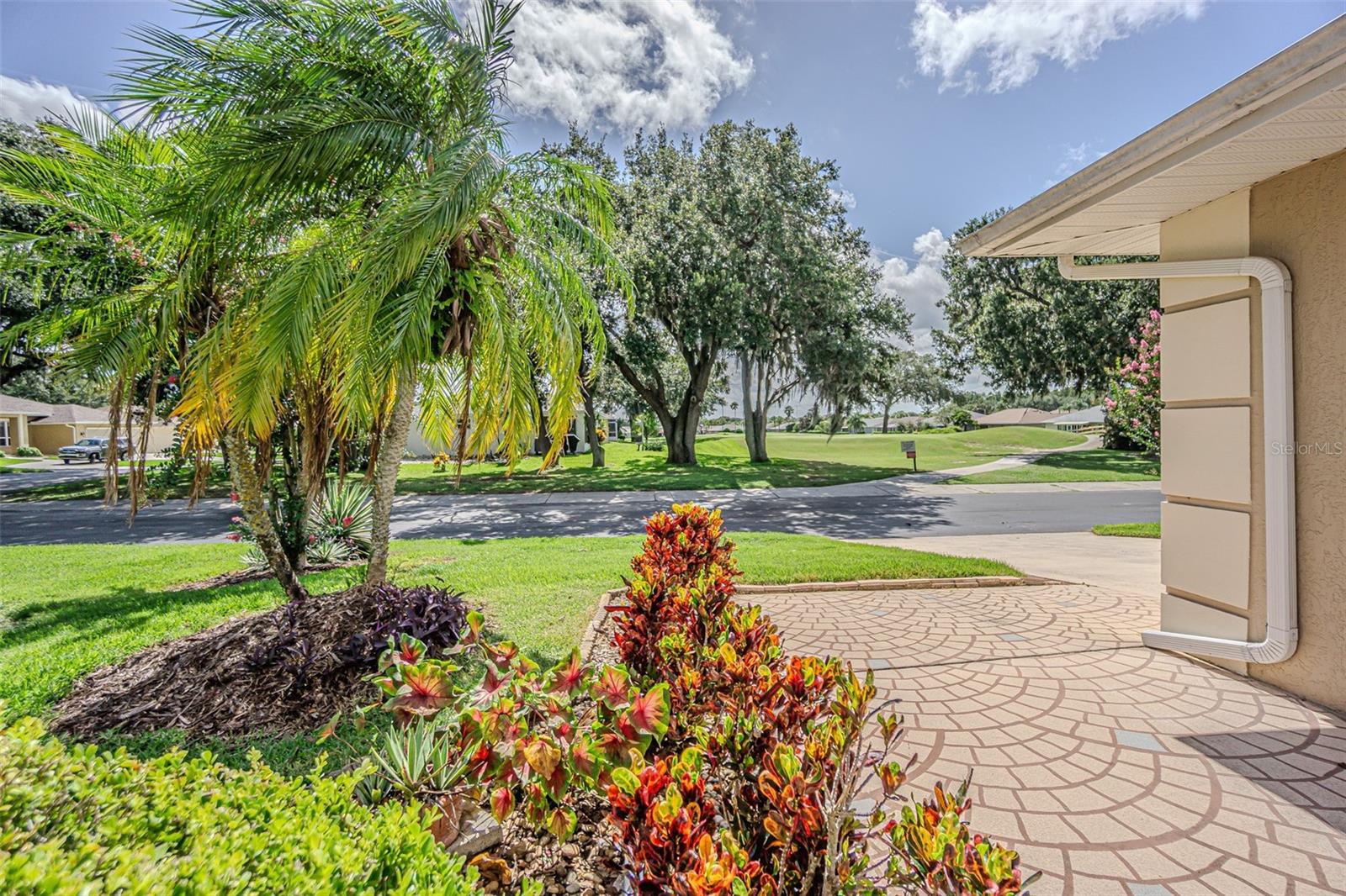 Tropical landscape welcomes you with decorative concrete walkway and screened front entry.