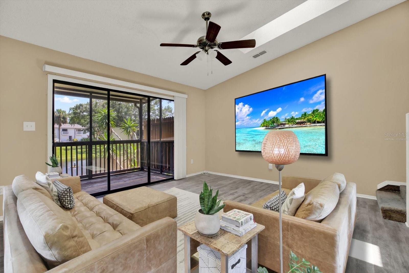 *Virtually staged* second level living room with pond/water view, high ceilings with skylights. Laminate flooring.