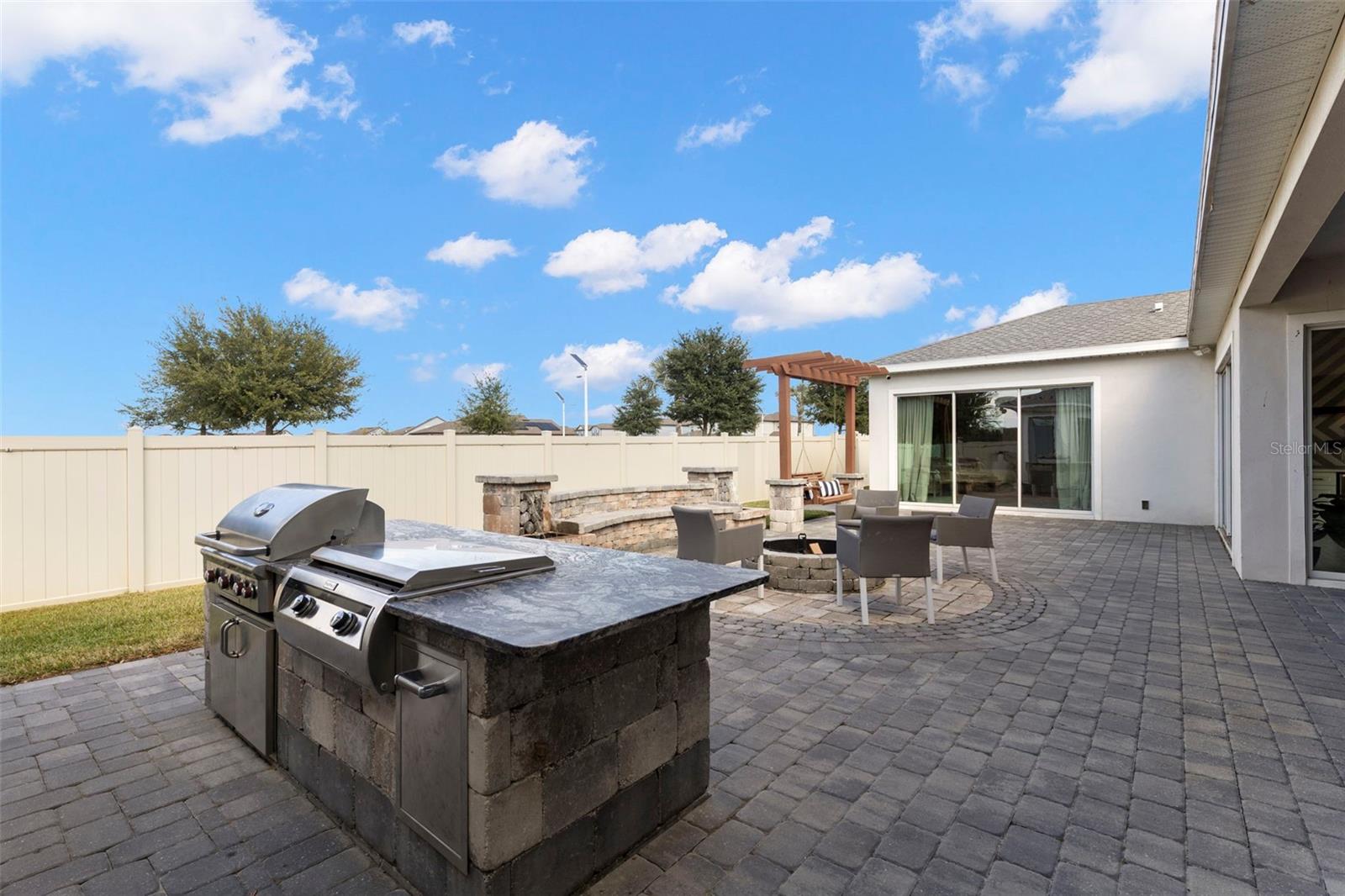 The courtyard is a showstopper with artisan stone finishes, a built-in summer kitchen (AOG grill, Fire Magic Gourmet Griddle, mini fridge), granite countertops