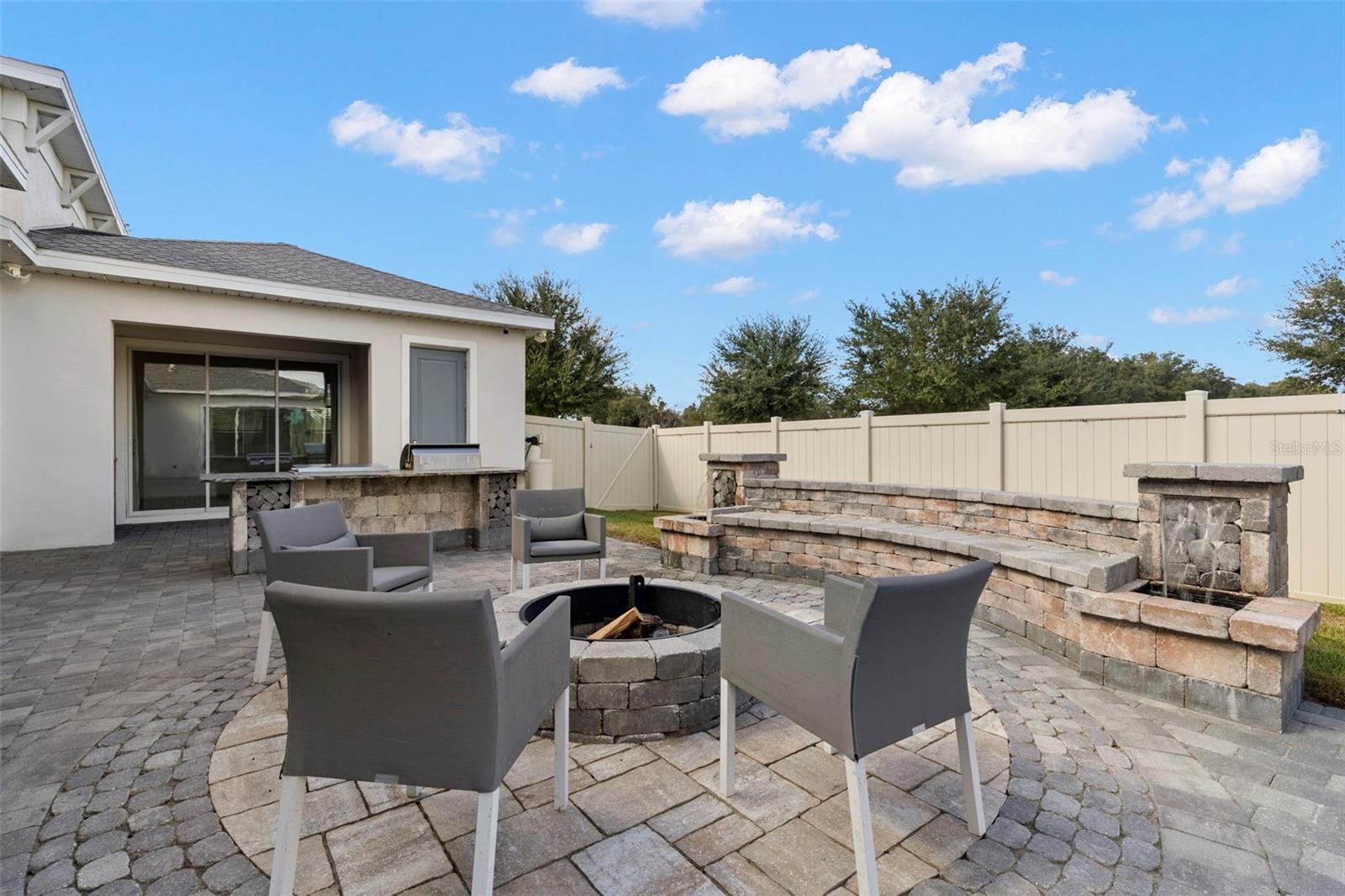 fire pit with custom stone seating, dual waterfalls, a pergola with swing, and a natural mosquito repellent system.