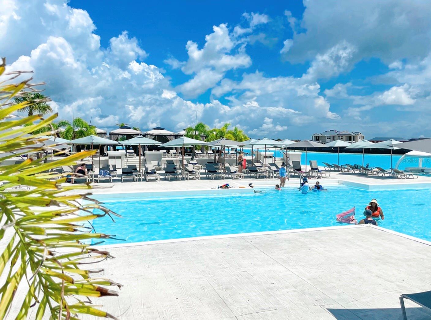The lagoon features a beach, swim-up bar, water slide, climbing wall, kayak and paddleboard rentals, and an entertainment pavilion with a stadium-sized LED screen