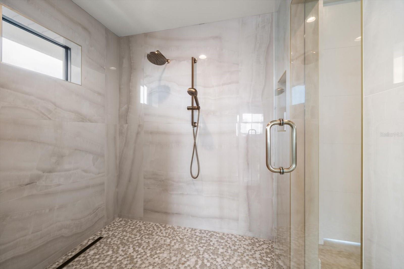 Primary suite walk in shower -superbly finished in fine stone work and custom fixtures.