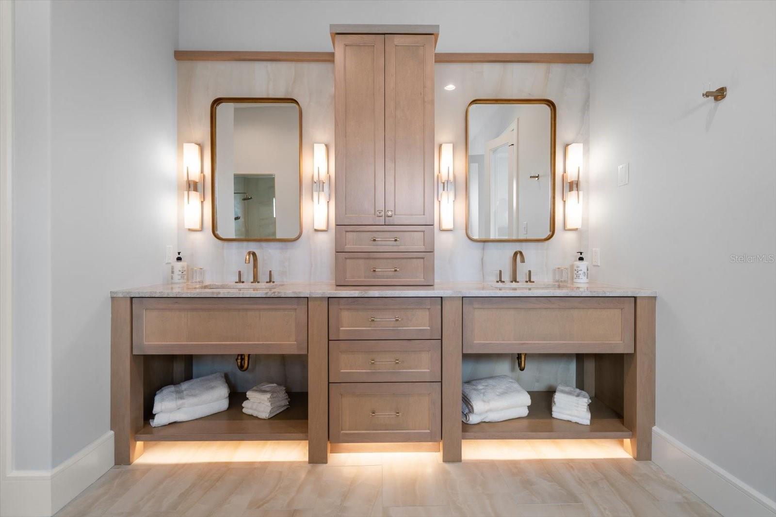 Vanity area in primary suite offers tower storage, impressive fixtures and natural stone wall application.