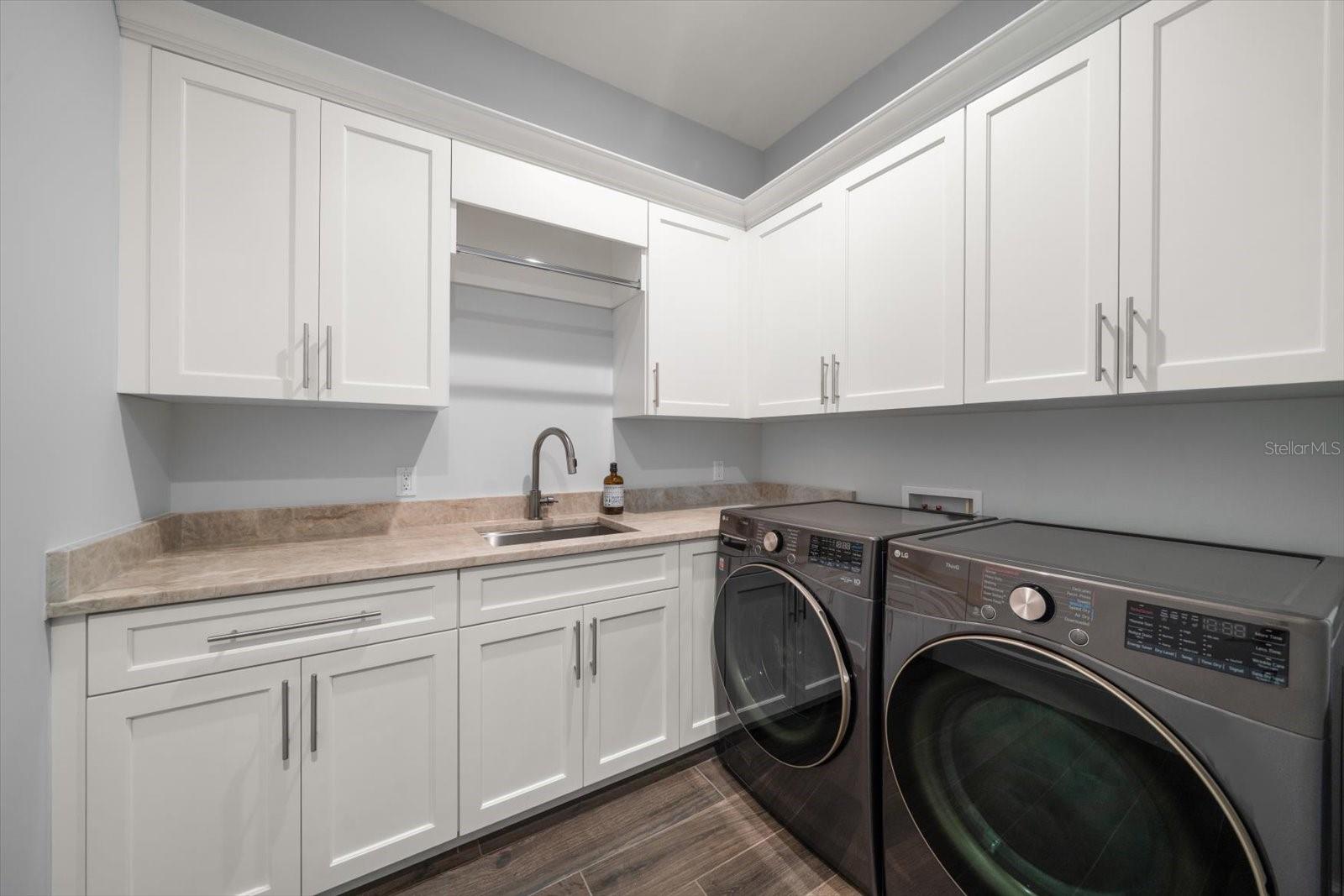 Laundry room has extensive storage, built in sink and full capacity washer dryer.