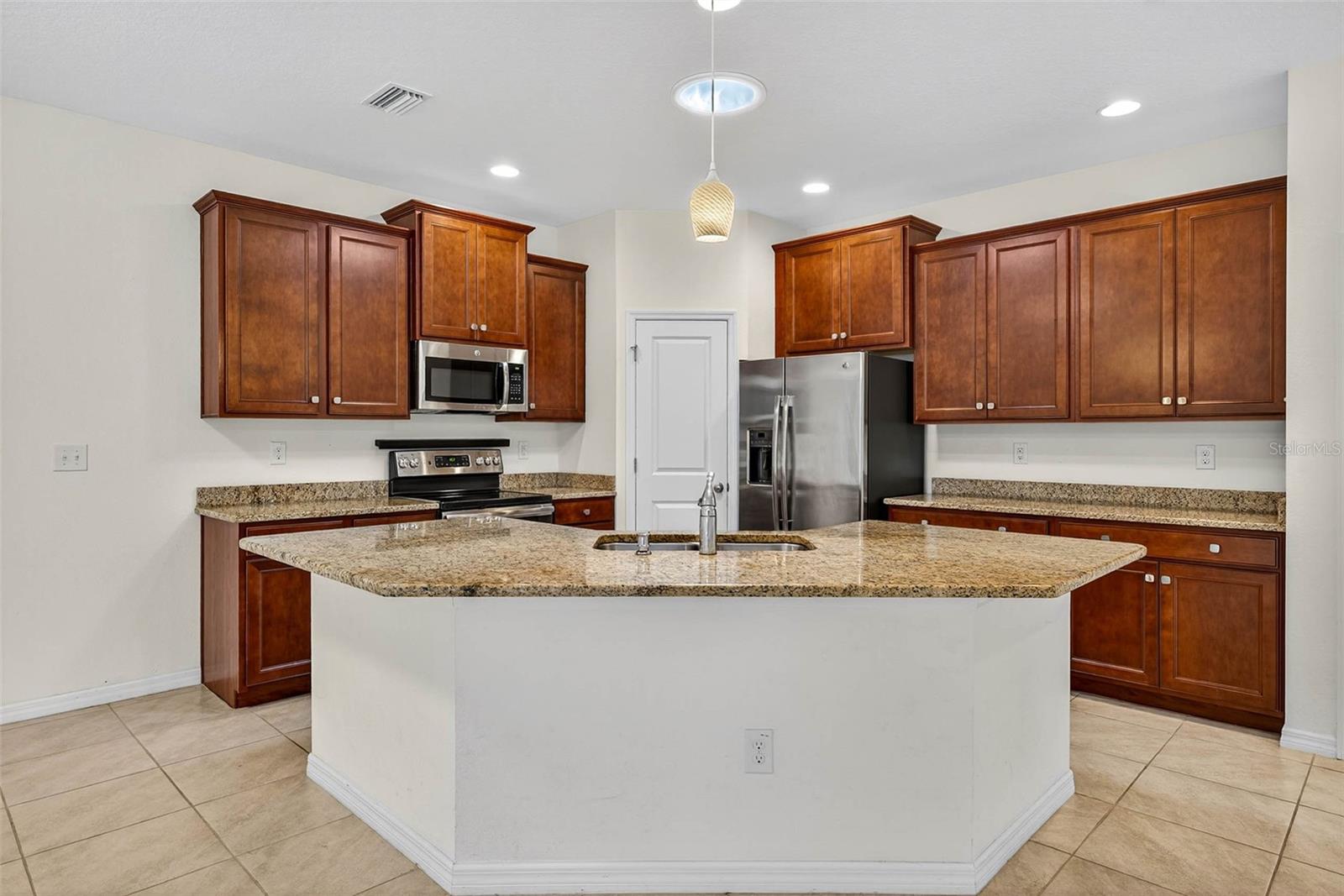 Kitchen has granite countertops, wood cabinetry, closet pantry, and stainless steel appliances.