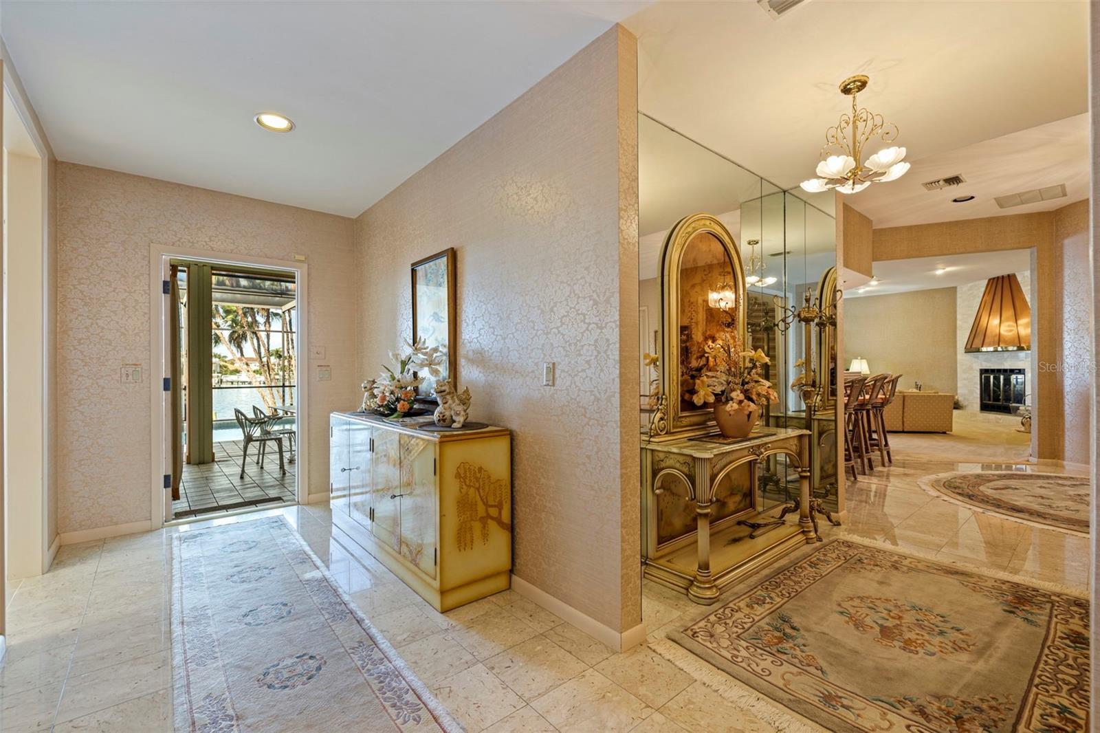 From this spot in the hallway, the kitchen is on the left, the open door leads to the pool deck and to the right you can see all the way back to the family room