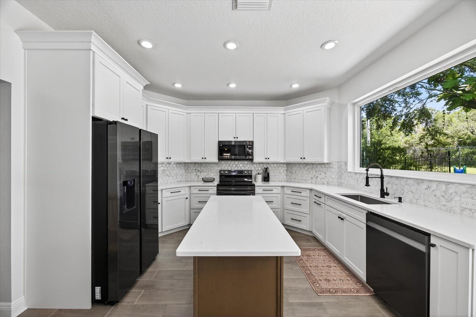 Newly updated kitchen featuring black stainless stell appliances, quartz countertops