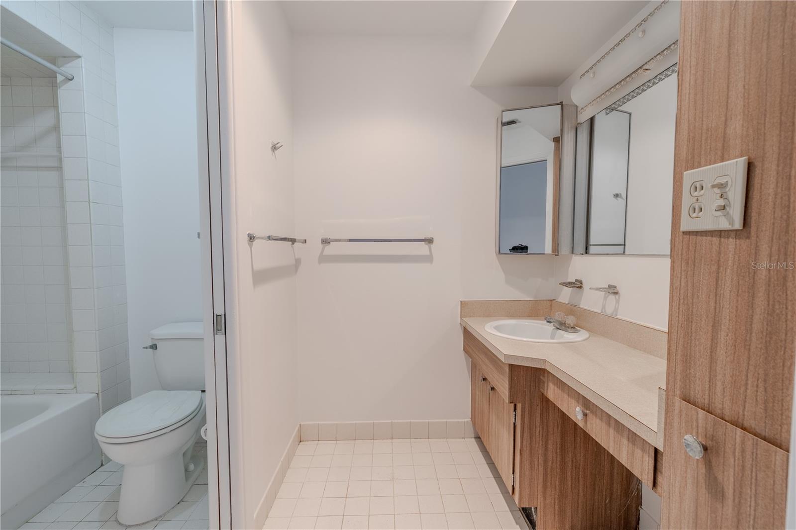 A tub-shower combo with classic square tiles offers versatility and convenience. Dual towel bars and thoughtful lighting above the mirror make this a functional space that’s ready for your personal updates or mid-century modern revival. Whether you're starting fresh or looking to modernize, this bathroom provides a solid foundation with generous space and vintage charm.