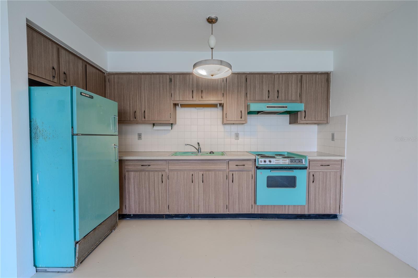 The retro-chic kitchen showcases vintage turquoise appliances that add a pop of personality and nostalgic charm.