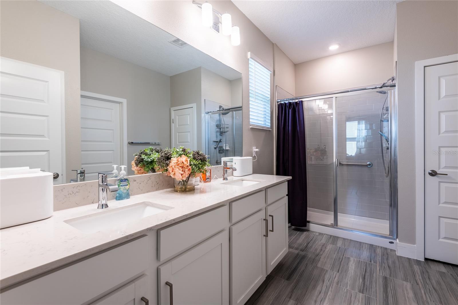 Primary bathroom with dual sinks. Quartz countertops and shaker wood cabinets. Stand-up shower.