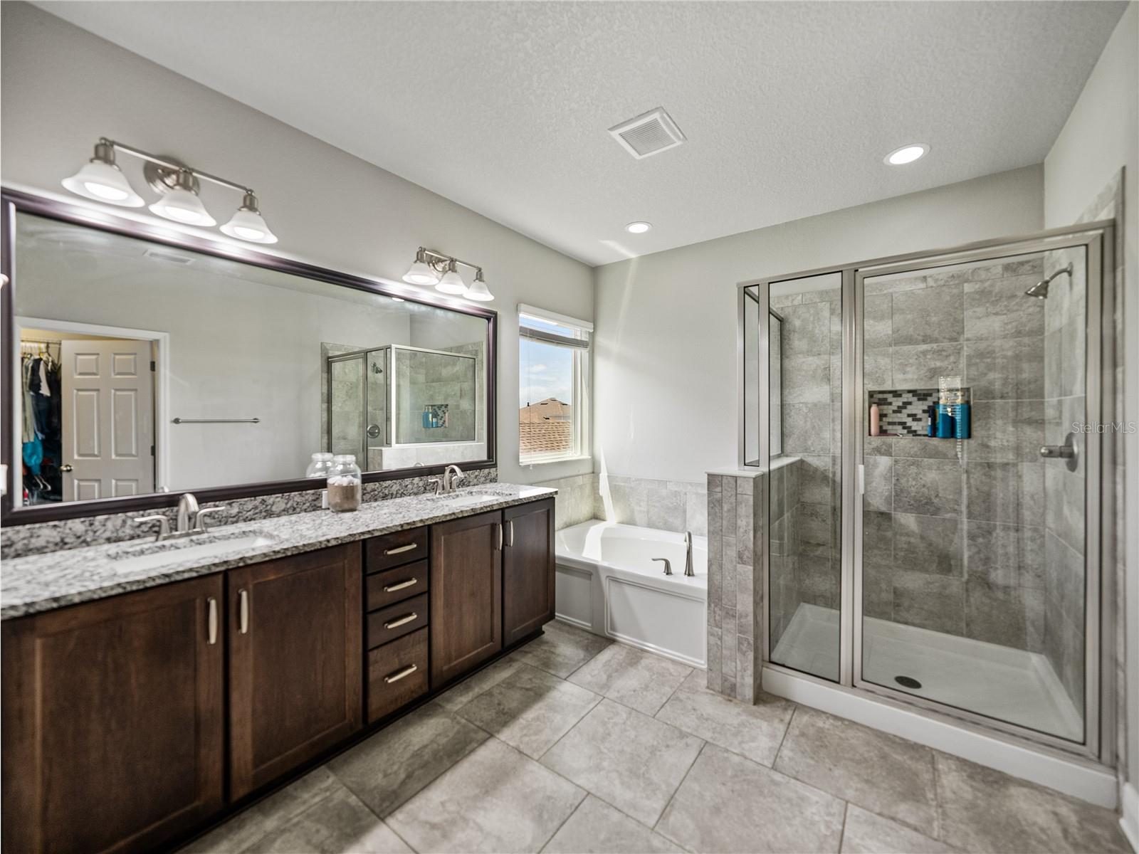 Primary bathroom features stone tops, soaker garden tub and walk in shower
