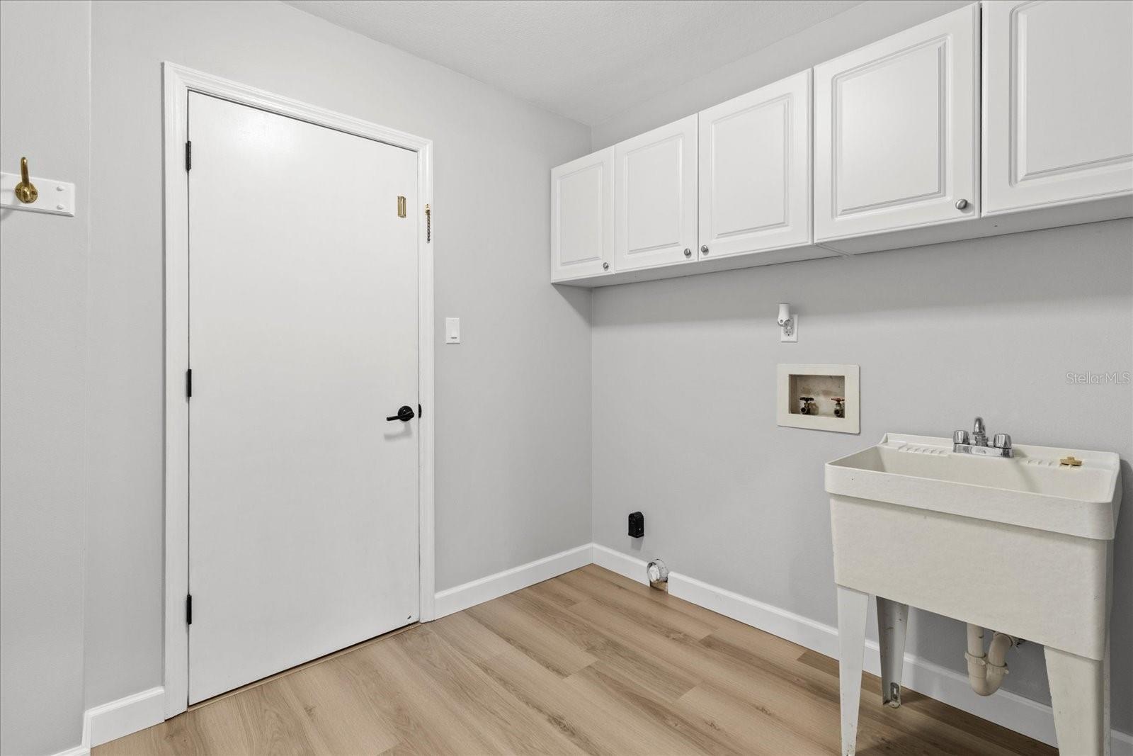 Laundry room with storage cabinets and entry to garage