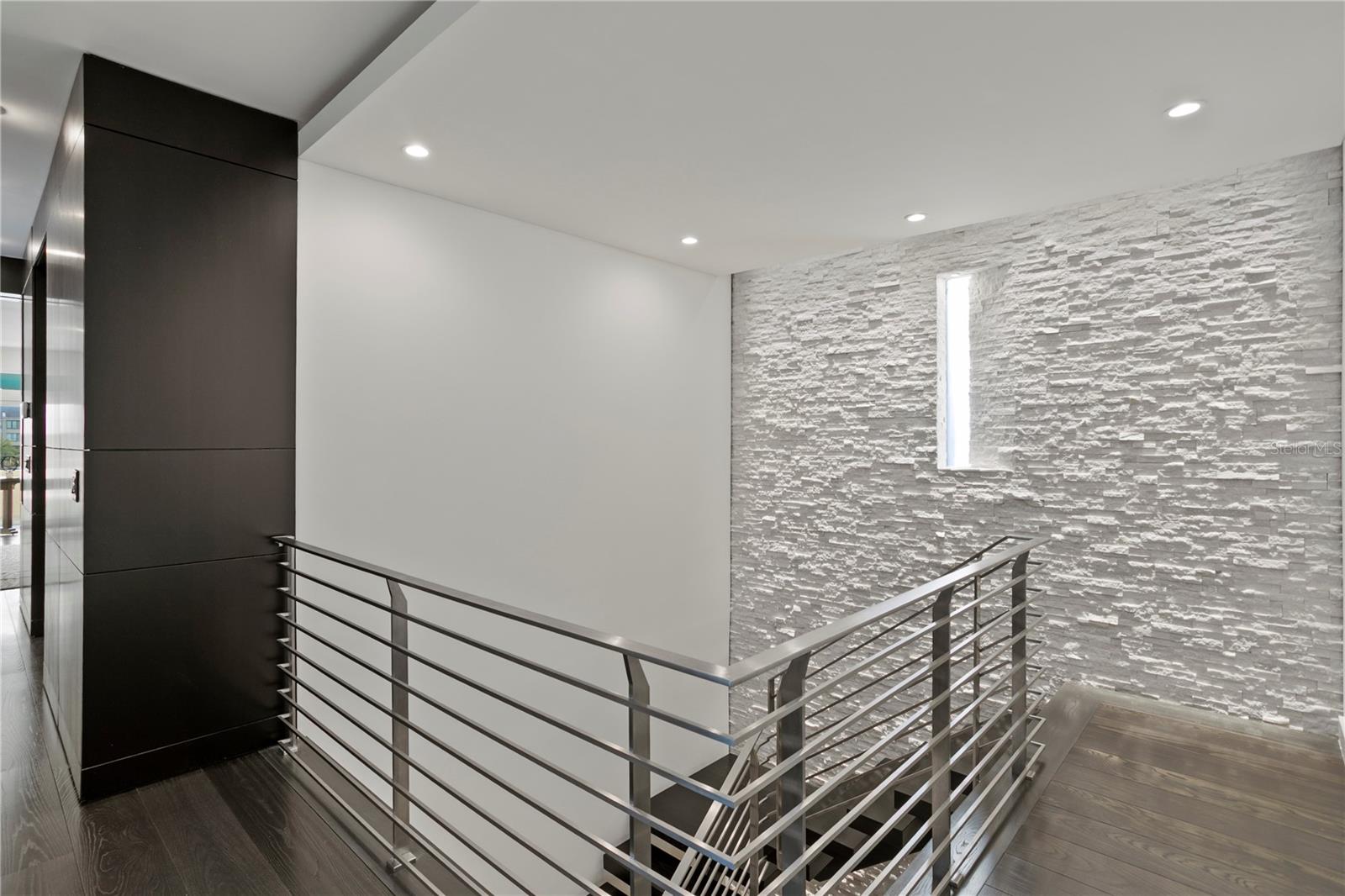 Textured stone wall extends from Entry Hallway/Foyer all the way to Primary Level with specialty lighting