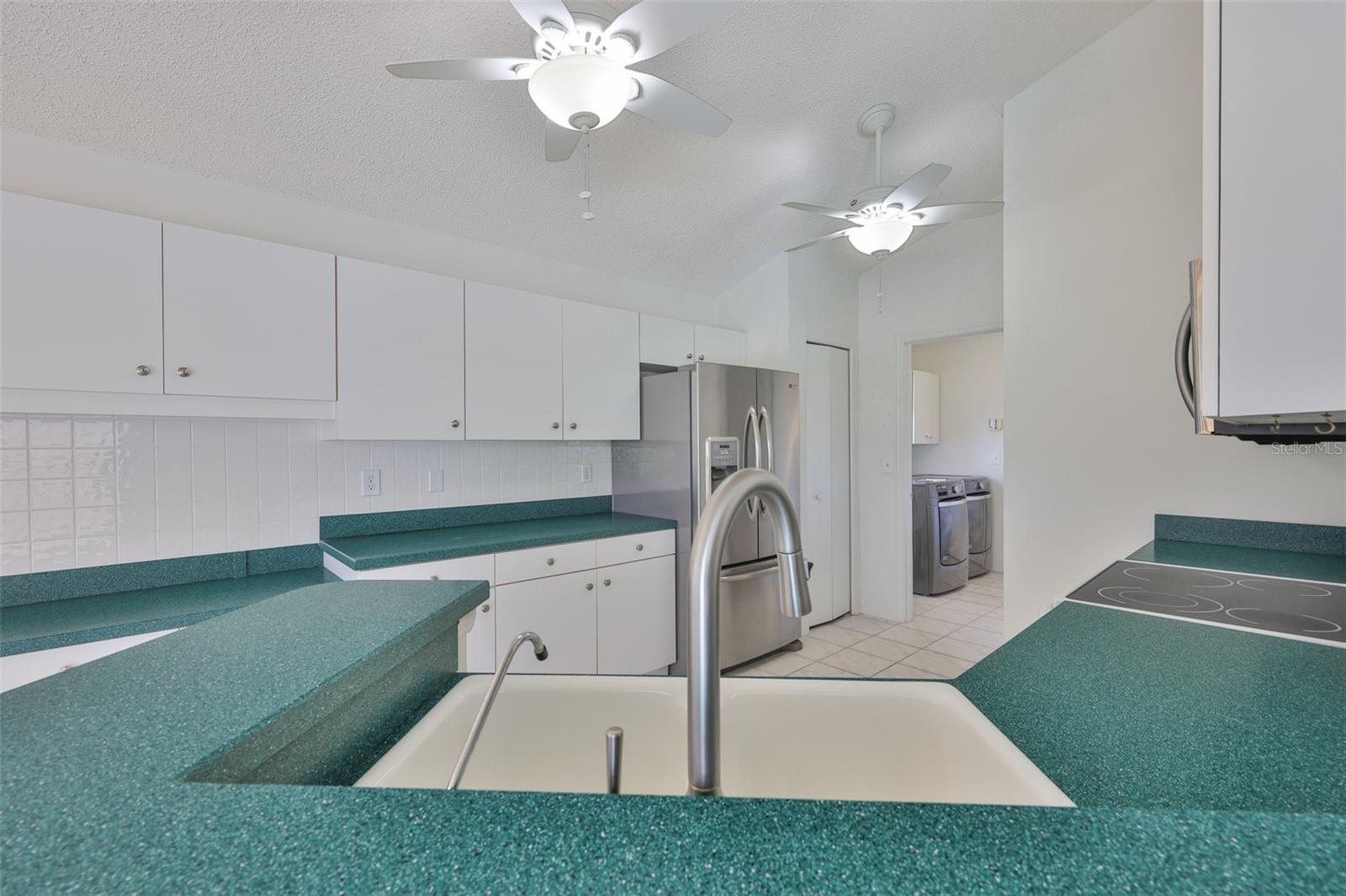 Tiled backsplash and pantry next to the french door refrigerator. Kitchen sink has a drinking water spigot with purified water by reverse osmosis.