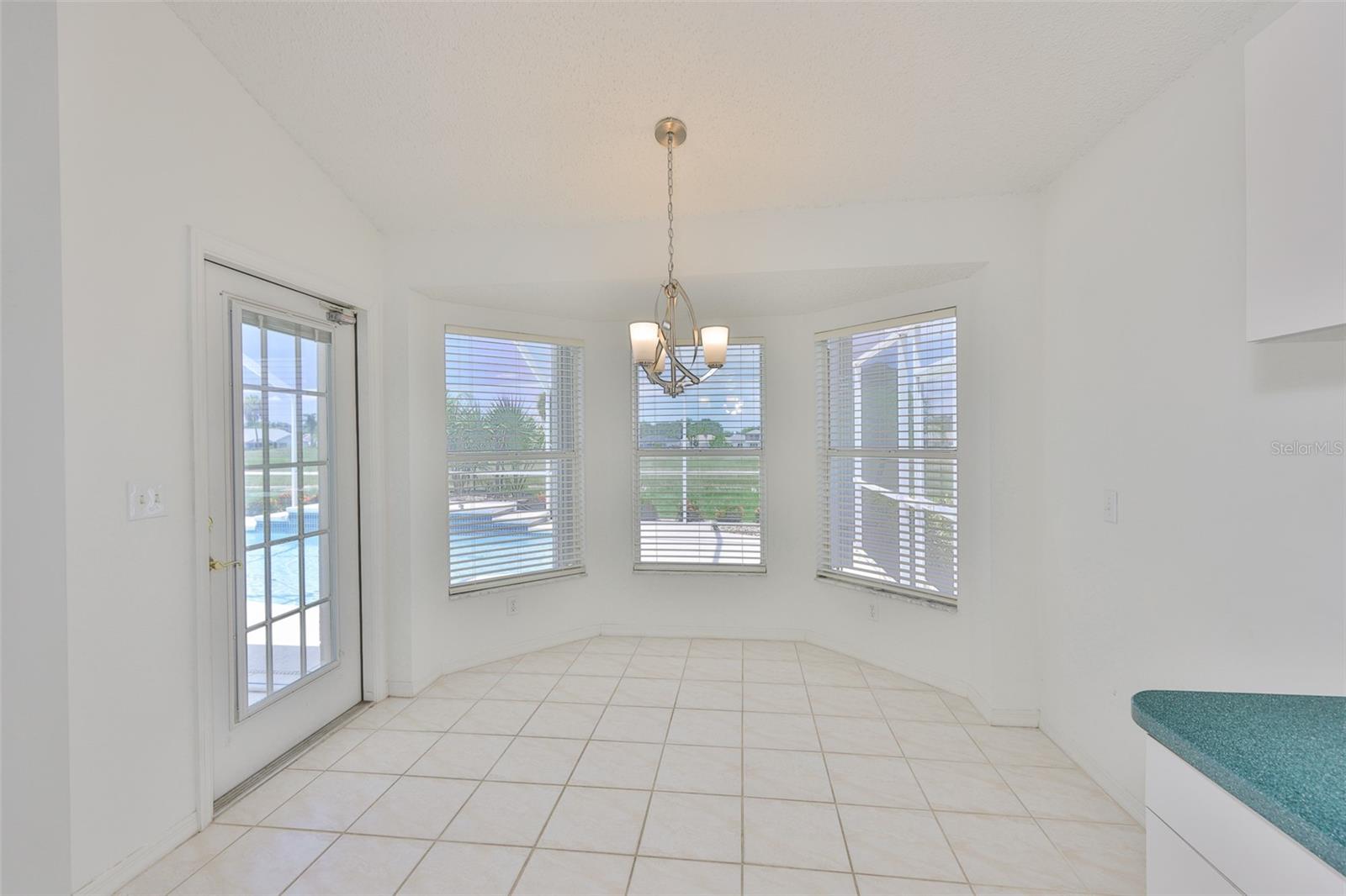 Dinette with new ceiling fixture, pool/lanai door (blinds inside the door itself for privacy) and pool, water and conservation views.