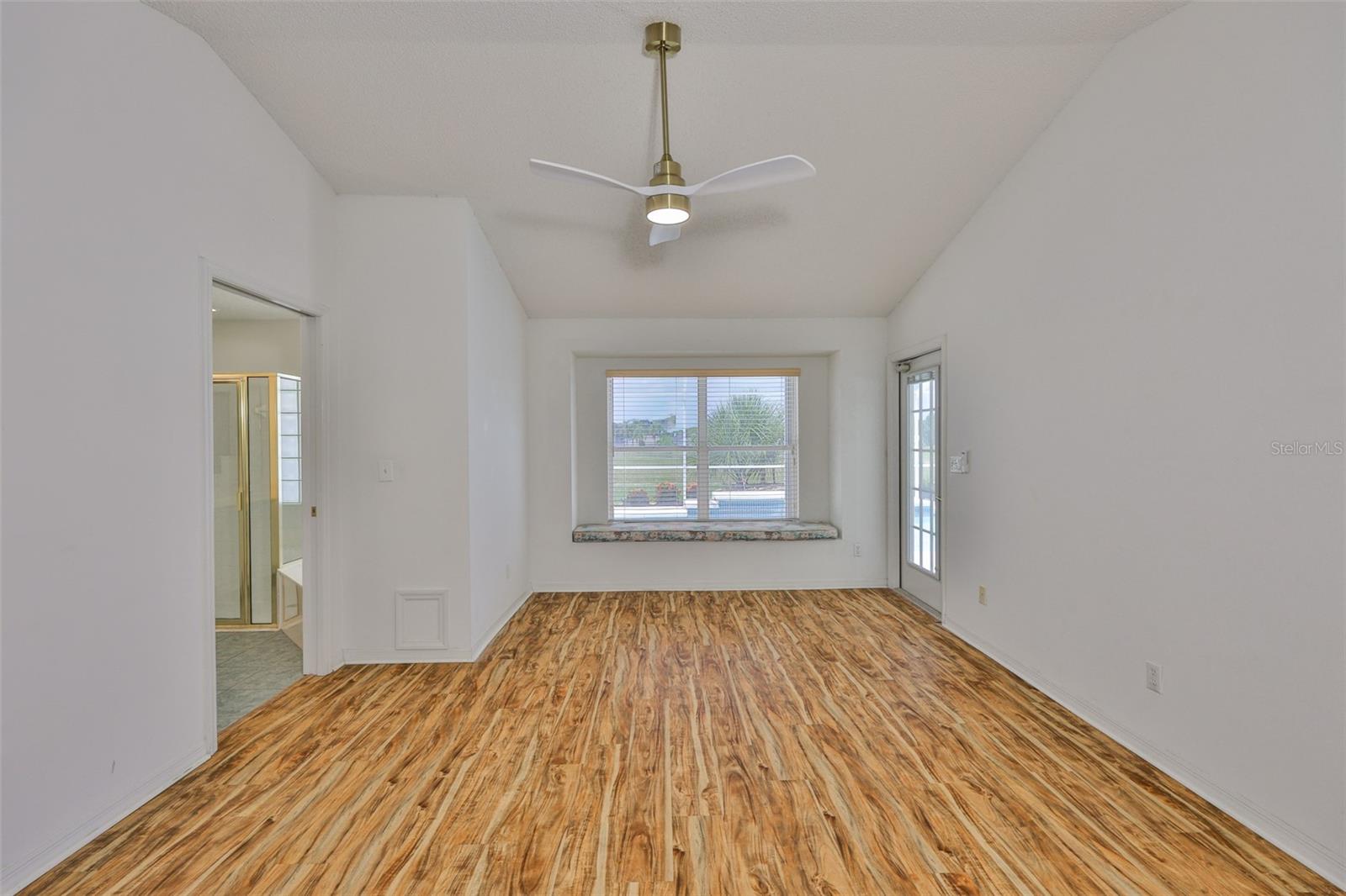 Primary bedroom, pool view and window seat, new ceiling fan. Primary bath suite on left, pool/lanai door on right.