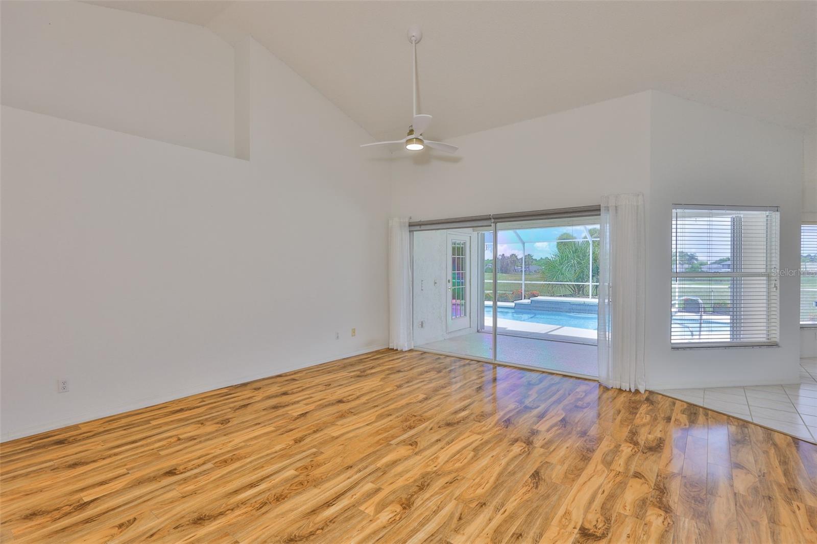View the openness with the light filled great room with vaulted ceiling and slider to pool and lanai. Kitchen and dinette on right.