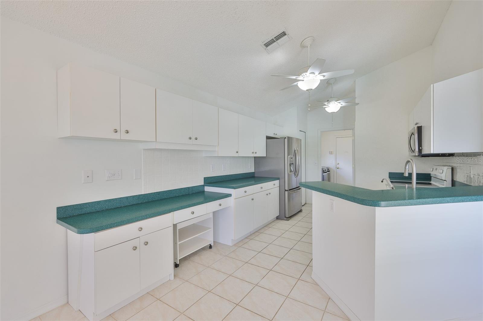 Expansive kitchen from dinette. Cabinets galore, built-in desk, stainless refrigerator, microwave and dishwasher. Sual sinks with stainless spray/regular faucet. Two ceiling fans keep it cool, even when the oven is on!