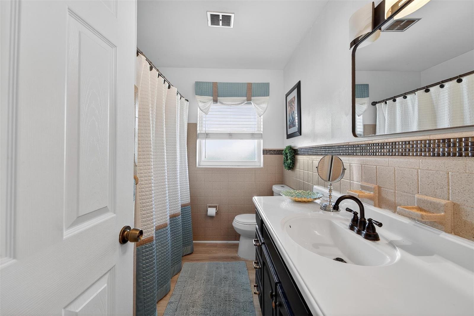 Updated second full bathroom featuring neutral finishes, a modern vanity with ample storage, and a bright window—perfect for family use or guests