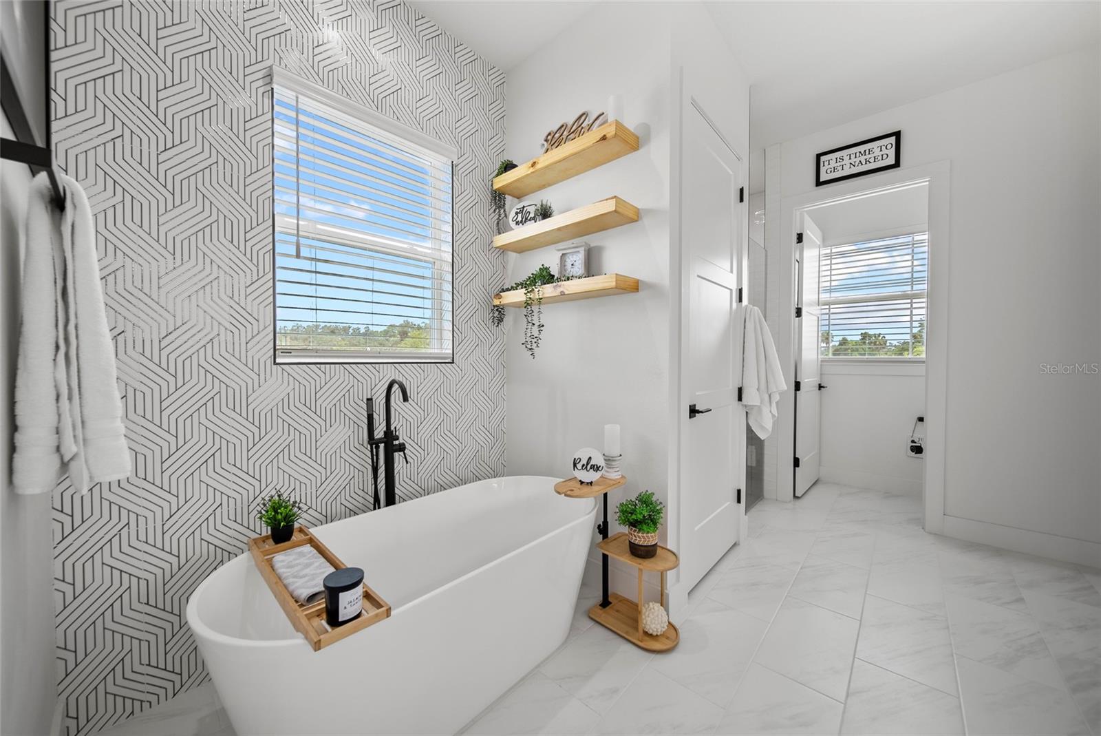 soaking tub & custom designer tile throughout primary bathroom