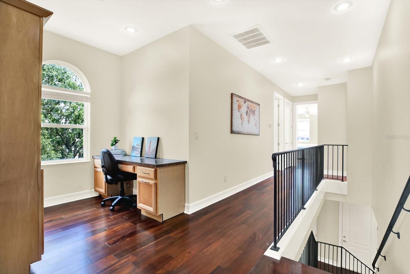Loft area with built in desk and shelving unit, perfect for work or studying.