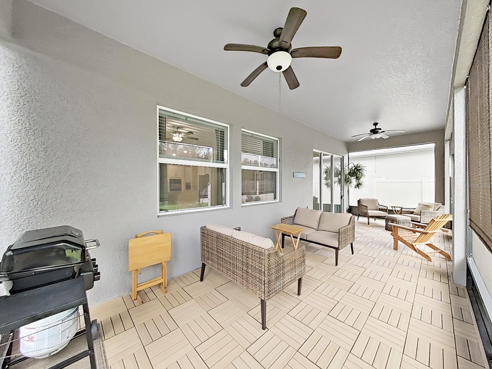 Screen covered patio with fans, pull down blinds and custom plank flooring.