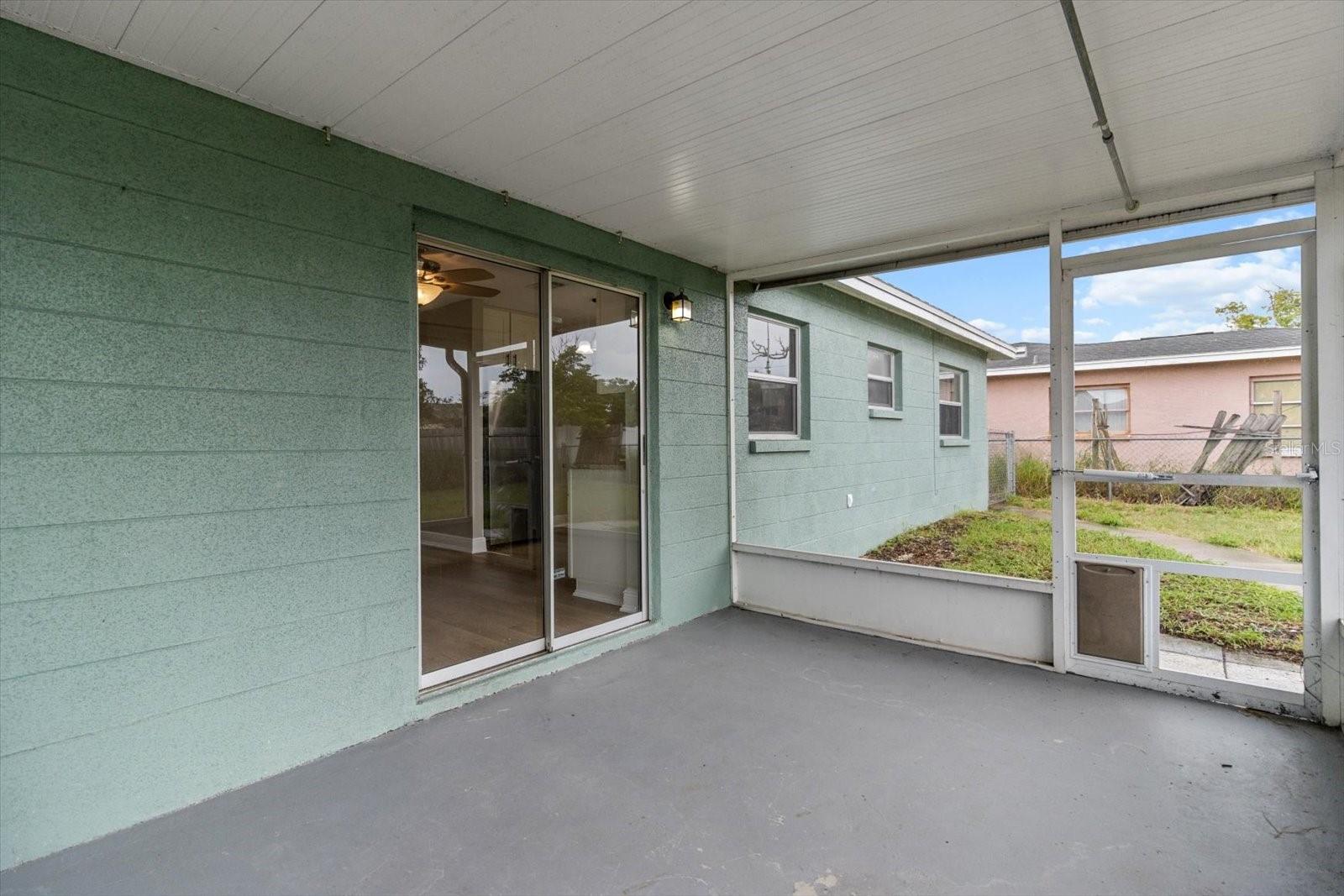 Covered outdoor space with sliding glass doors offering direct access to the kitchen, perfect for easy indoor-outdoor dining and entertaining.