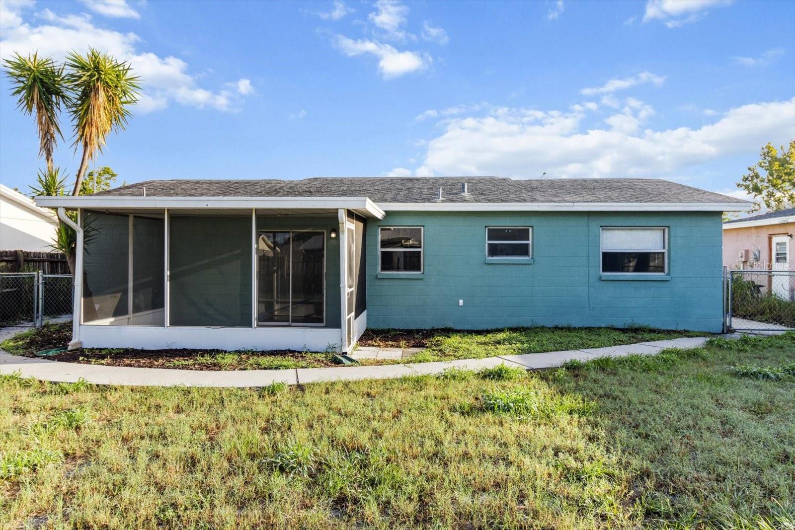 Concrete walkway runs from one side of the house to the other, connecting both gates and leading directly to the screened porch for convenient access all around.