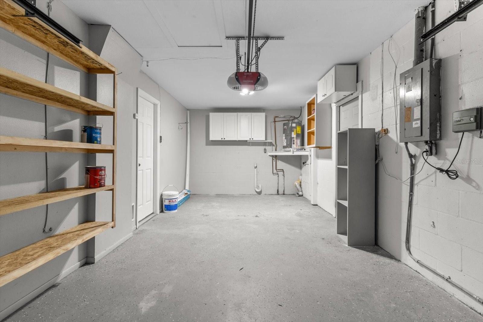 Functional space with washer and dryer hookups, storage shelves, and cabinets
