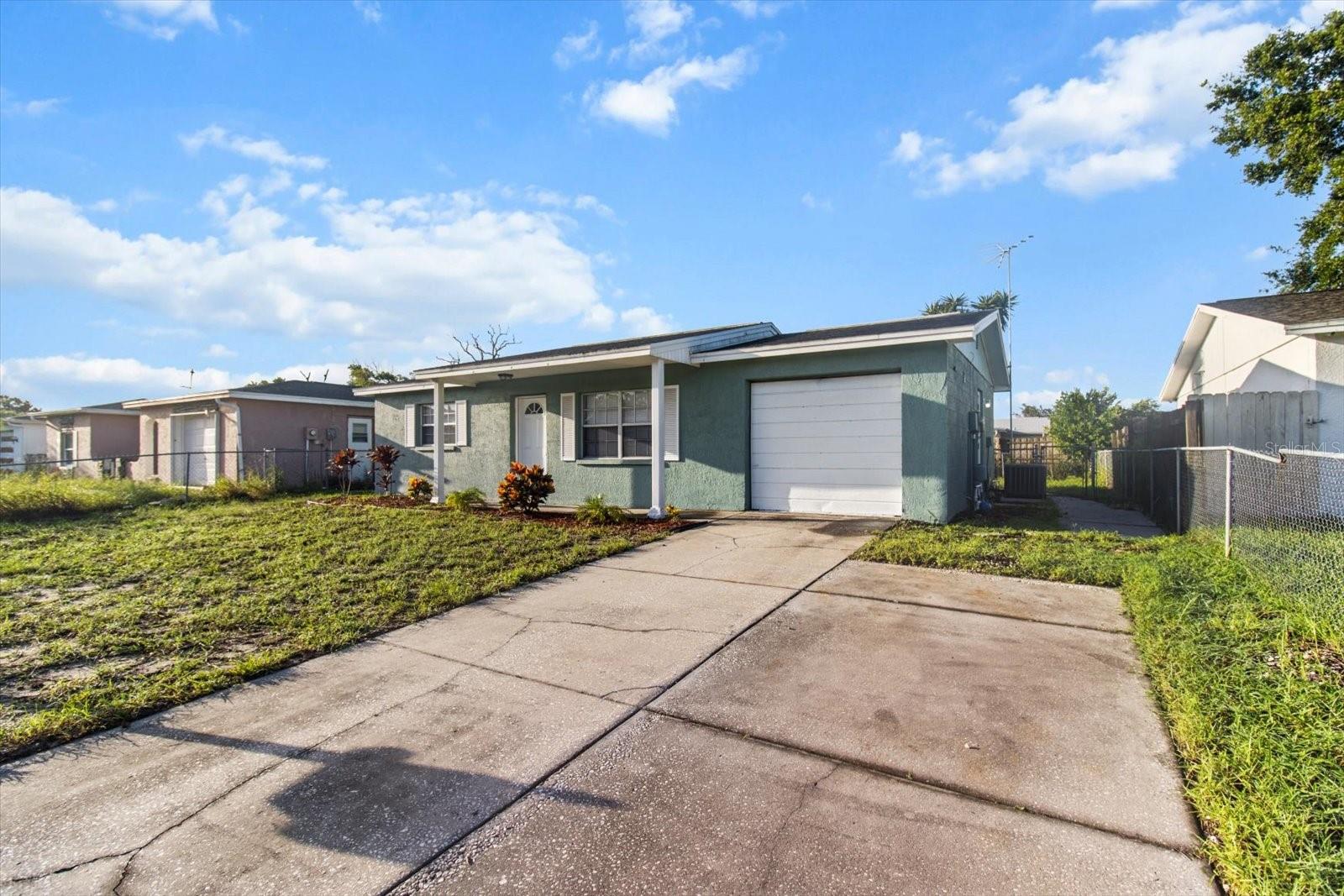 Extended driveway leads to a side door and gated walkway—offering easy access to the backyard, garage, and screened porch without stepping through the front door.