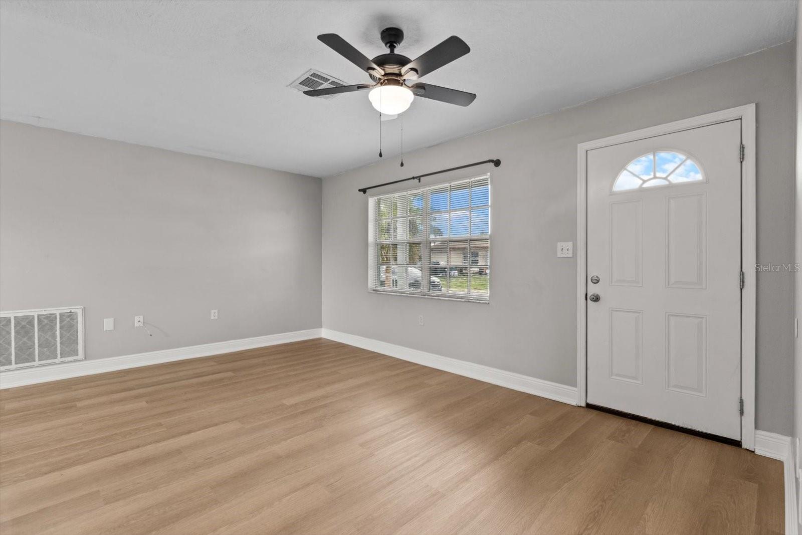 Bright and airy living room with updated vinyl flooring and modern ceiling fan.