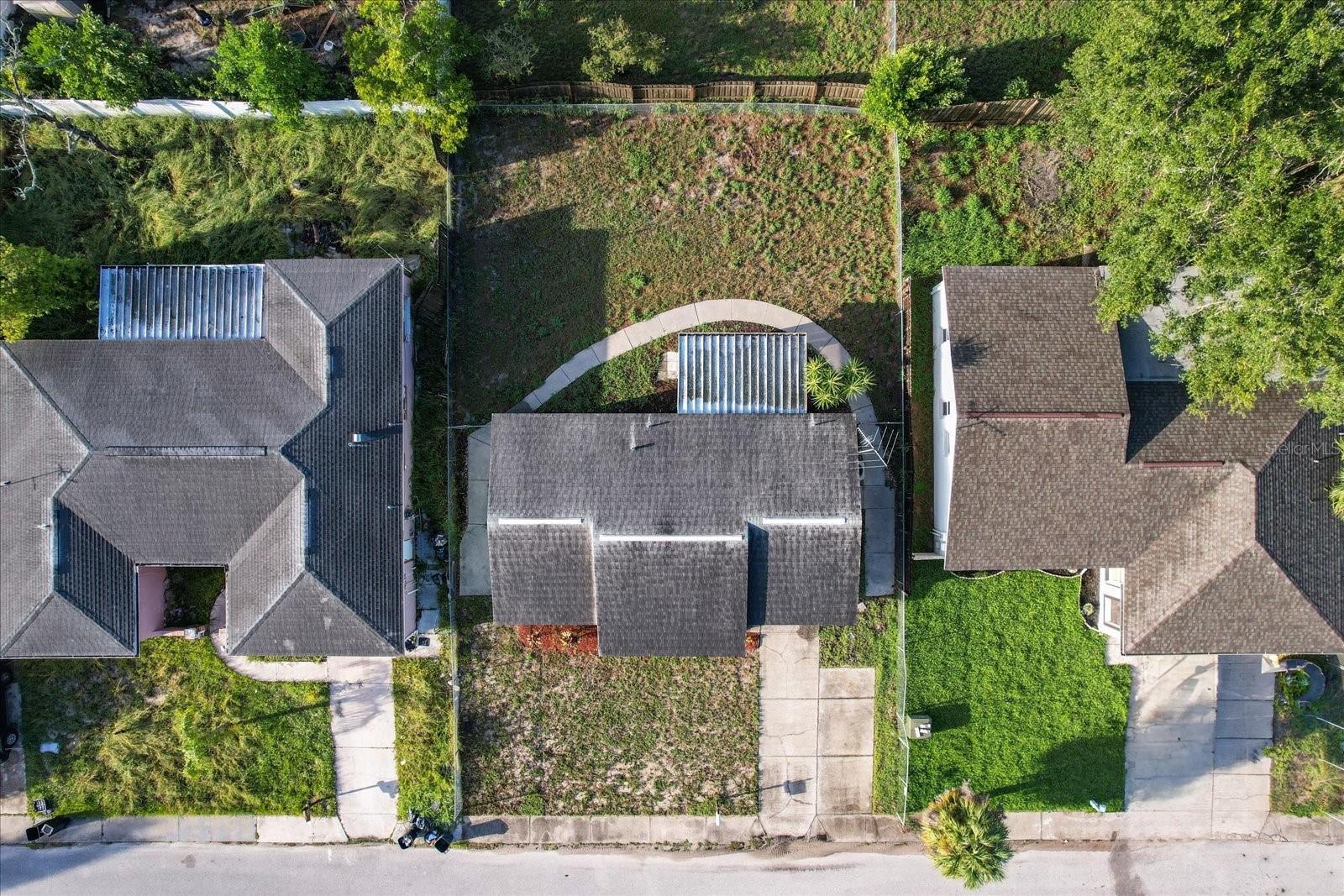 Aerial view of the home, fenced backyard and wrapping around walkway.