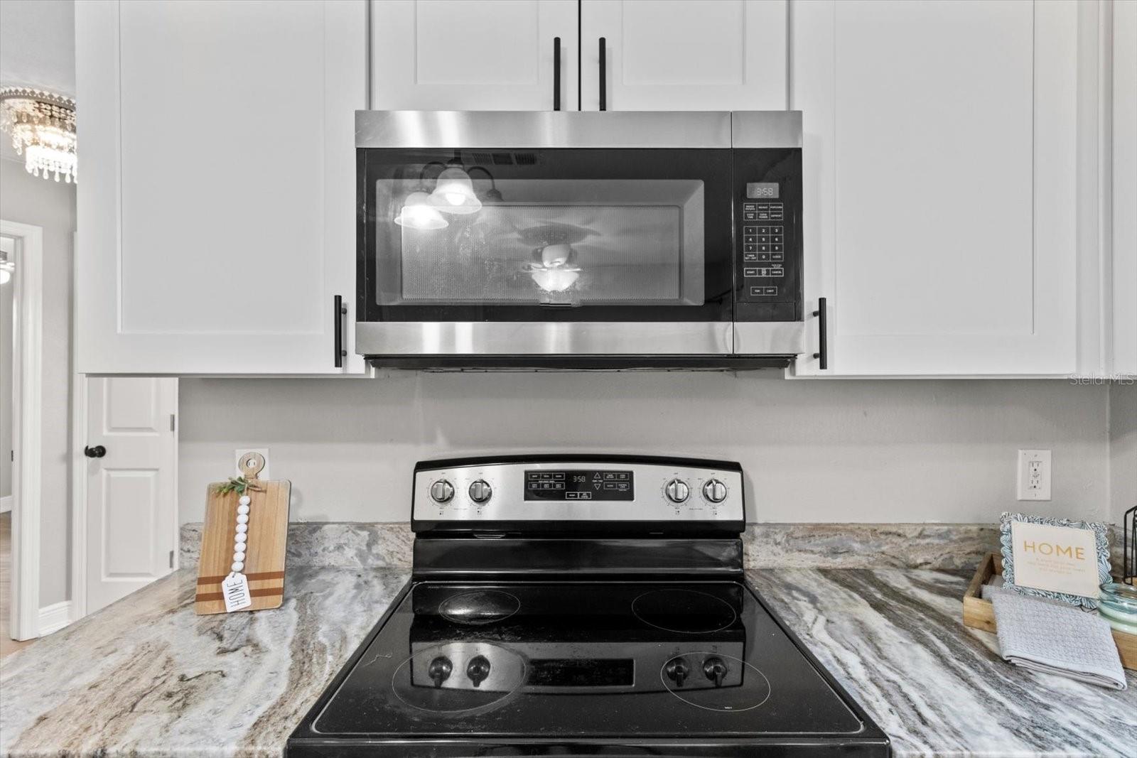 stainless steel range and microwave surrounded by fresh cabinetry and beautiful countertops, ready for your next home-cooked meal.