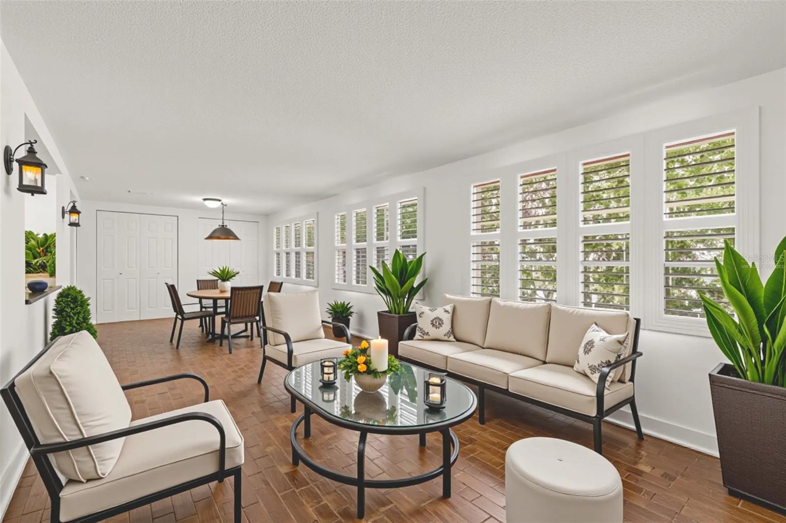Florida room virtually staged looking out through plantation shutters