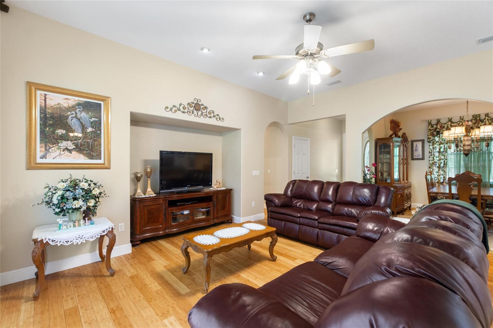 Living room with ceiling fan and bamboo flooring.