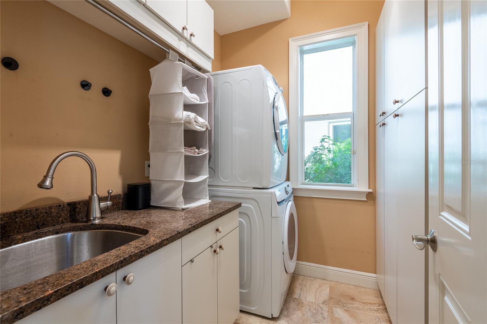 Large laundry room with full size washer and dryer, sink and lots of cabinets and closet space.